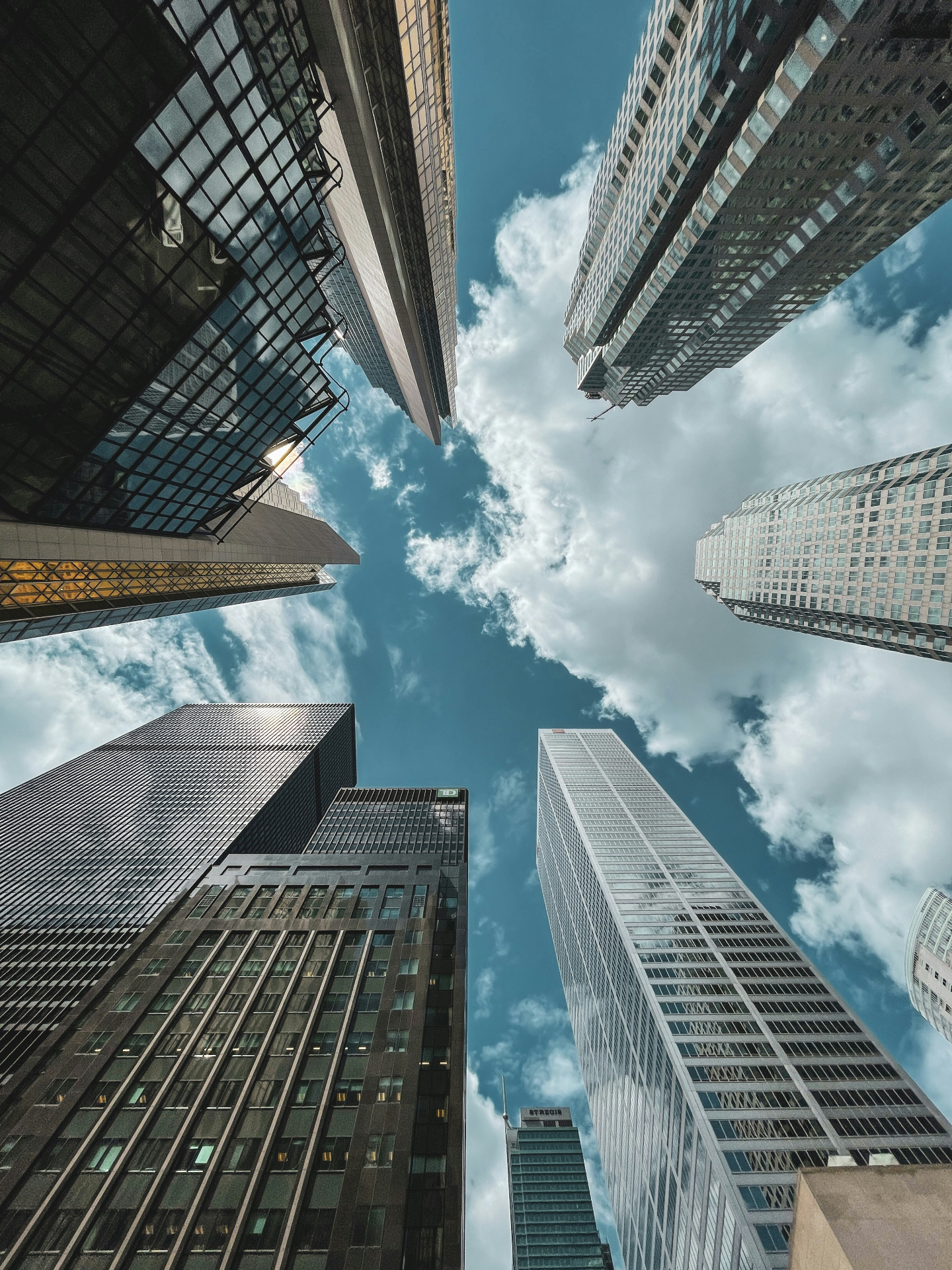 Upward view of downtown skyscrapers against a cloudy sky, representing EB-5 real estate development projects under I-956F regional center review