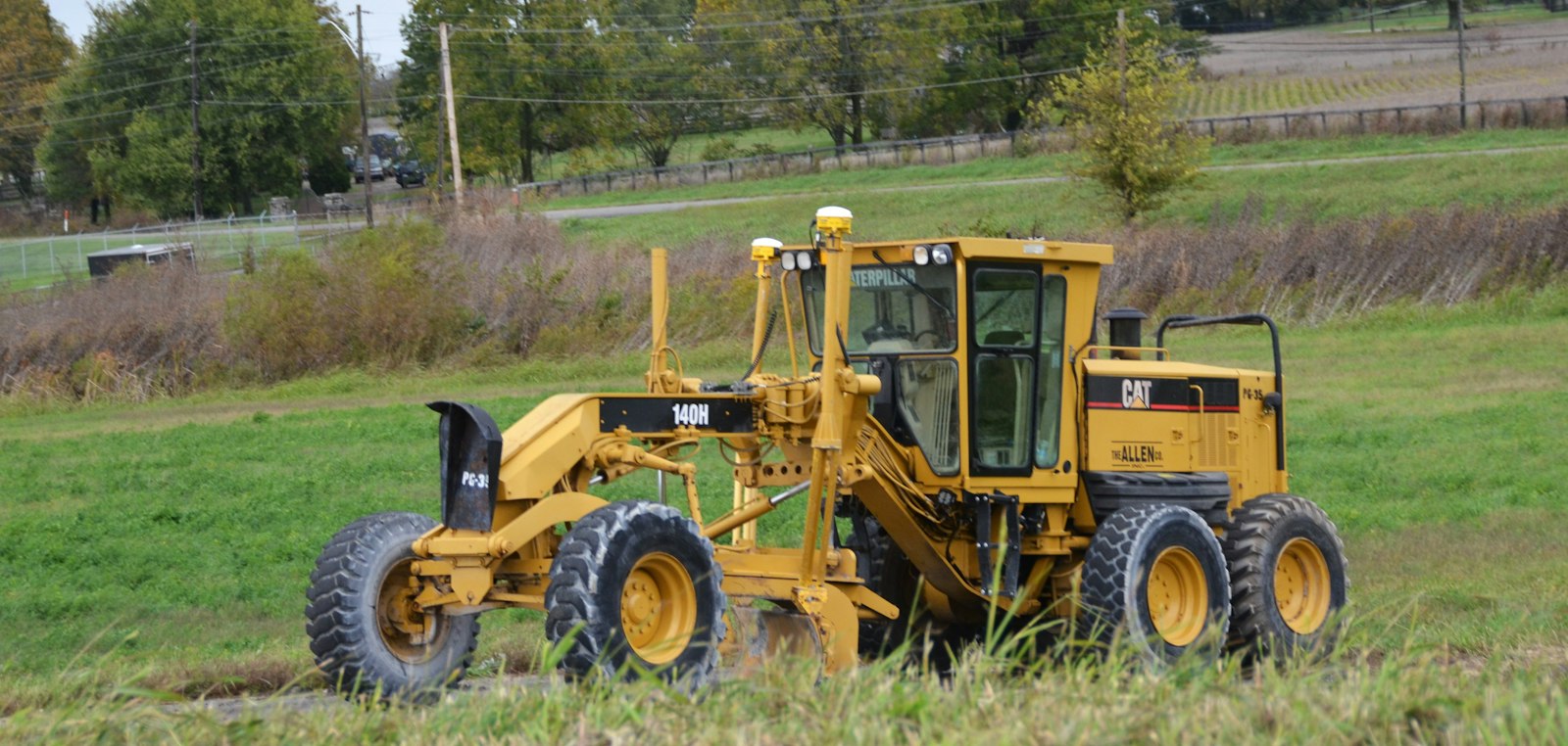 Yellow motor grader parked in a grassy field